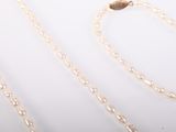 two pieces of gold chain on a white surface