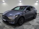 un SUV Tesla gris garé dans un garage au sol à damier