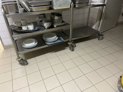 a kitchen with a stainless steel cart with plates and pans on it