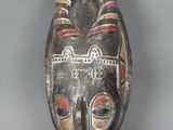 une image représentant un masque en bois muni de cornes sur fond gris