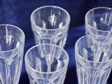 four clear glasses are lined up on a blue cloth