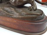 bronze statue of a lion on a rock on a wooden base