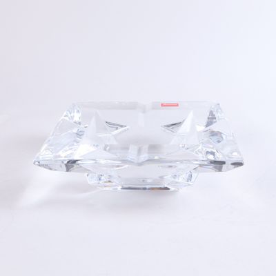 un cendrier en verre transparent avec une poignée rouge sur fond blanc