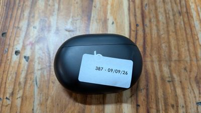 des AirPods noirs posés sur une table en bois