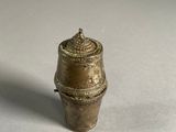 a small brass object on a white surface