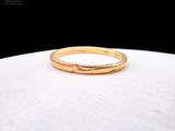 un gros plan d'une bague en or posée sur une surface blanche