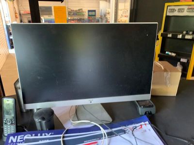 un écran d'ordinateur posé sur un bureau, à côté d'une télécommande