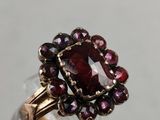 a close up of a ring with a red stone surrounded by purple stones