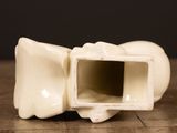 a white vase with a hole in it on a wooden table
