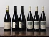 six bottles of wine are lined up on a wooden table