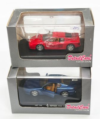une paire de petites voitures moulées sous pression, rouge et bleue, dans leurs boîtes, posées sur une surface blanche