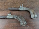 pair of old guns sitting on a wooden table on top of a table