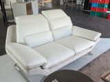 un canapé en cuir blanc dans un salon avec une table basse