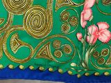 green and gold embroidered fabric with pink flowers on a blue background