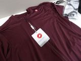 a maroon shirt with a tag on it sitting on a table