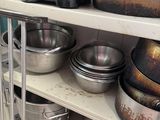 many pots and pans on a shelf in a kitchen