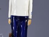 a statue of a man in a sailor outfit next to a suitcase