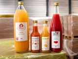 Plusieurs bouteilles de jus sont alignées sur une palette dans un entrepôt