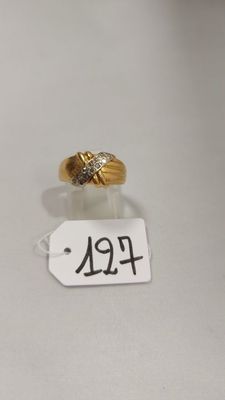gros plan d'une bague en or et diamants sur une surface blanche