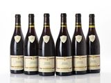 six bottles of wine are lined up on a white surface