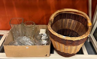 un panier en osier posé sur une étagère, à côté d'une boîte de verres à vin vides