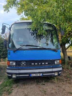 un bus bleu garé à côté d'un arbre