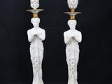 a pair of white statues with gold trims and a vase on top of them