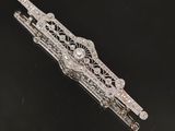 un gros plan d'une broche en argent et diamants posée sur une surface noire