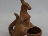 un petit kangourou en céramique tenant un bol dans la bouche
