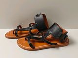 sandales en cuir noir avec des lanières noires sur un fond blanc