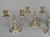three silver candlesticks and a clock on a table
