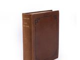 an old book with a brown cover sitting on top of a white surface