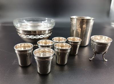 several shot glasses and a silver cup on a table