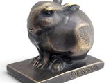 une sculpture en bronze représentant un lapin assis sur un socle