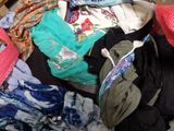 a pile of clothes that is sitting on a bed