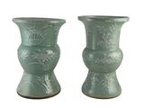 deux vases verts posés l'un à côté de l'autre sur une surface blanche