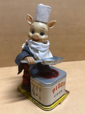 une figurine représentant un cochon coiffé d'une toque de chef et tenant un couteau
