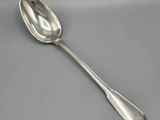 une cuillère en argent à long manche posée sur une table