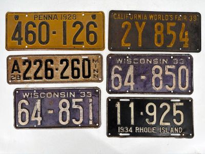 five different license plates on display on a white surface