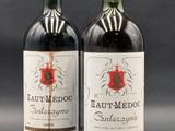 two bottles of red wine sitting next to each other on a table