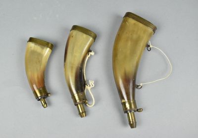 three horn shaped brass objects on a white surface