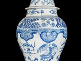 blue and white vase with a bird on top of it on a black background