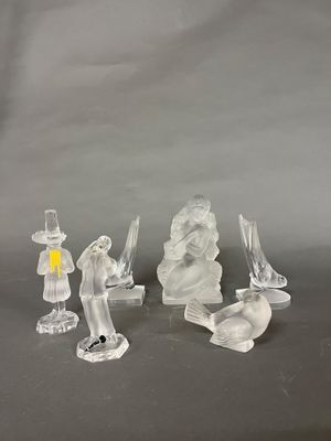 trois figurines en verre transparent sont posées sur une surface grise