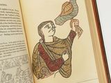 Quelqu'un tient un livre sur lequel figure le dessin d'un homme tenant un oiseau.