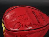 the red baseball glove has a lot of autographs on it