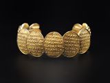 a gold cuff bracelet with a coin design on it