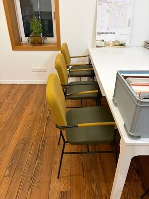 a white table with yellow chairs and a gray box on it