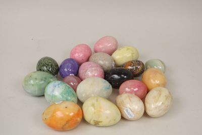 a pile of different colored eggs on a white surface