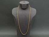 a gold rope necklace on a mannequin with a black background