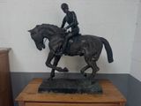 a statue of a man riding a horse on a wooden table